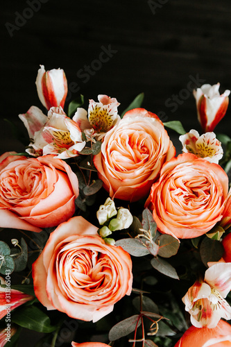  large luxurious bouquet of peony roses of coral color with white freesia in noir style on a dark background. dark romance