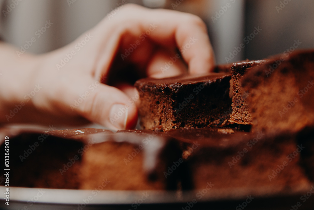 Pieces of chocolate sponge cake on plate, close up scene of woman hand grabbing a piece of cake. Pieces of chocolate sponge cake on plate, close up scene of woman hand grabbing a piece of cake.