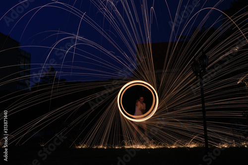 a long exposure photography of an steel wool on fire going in circles and dropping iron on fire as a shower