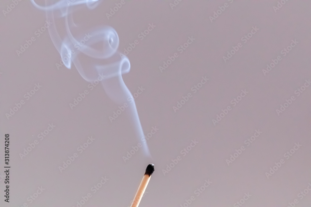 Match just extinguished with smoke in a grey background Match just extinguished with smoke in a grey background