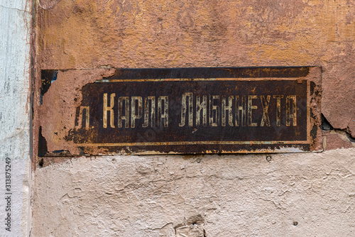 Russia, Artic, Barents Sea, Murmansk: Close up of barely legible street sign (Karl Liebknecht) in the city center of the famous northern Russian town on old broken house facade - remembrance travel