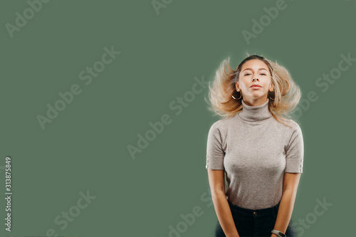Woman in grey golf standing against dirty green background