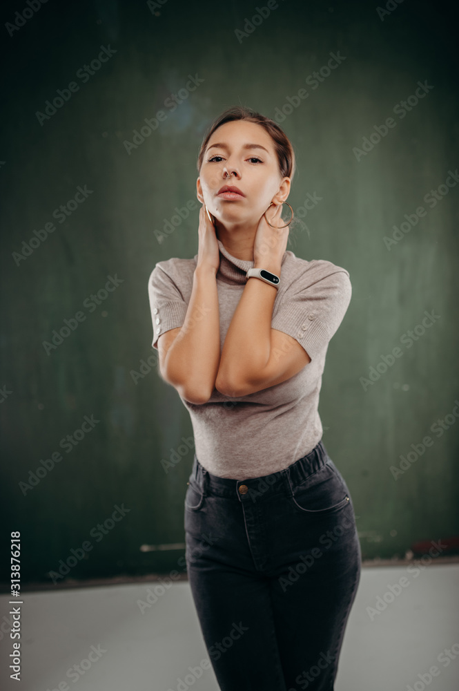 Woman in grey golf standing against dirty green background Woman in grey golf standing against dirty green background