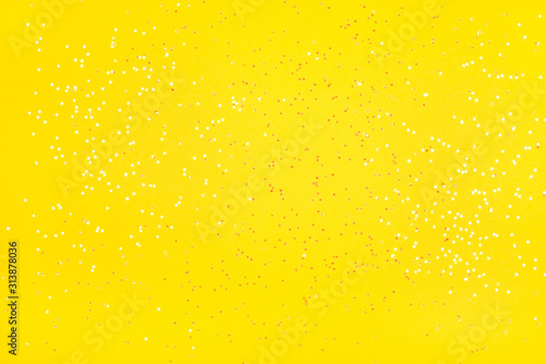 Tiny pearl stars on yellow background. Flat lay  top view.