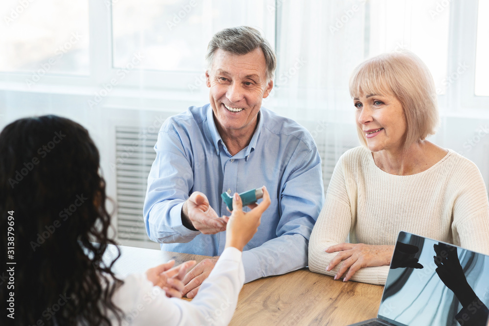 Female doctor giving blue inhaler to senior patient Female doctor giving blue inhaler to senior patient