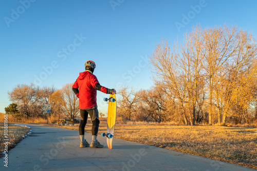 senior man with a cruising longboard on a bike trail photo