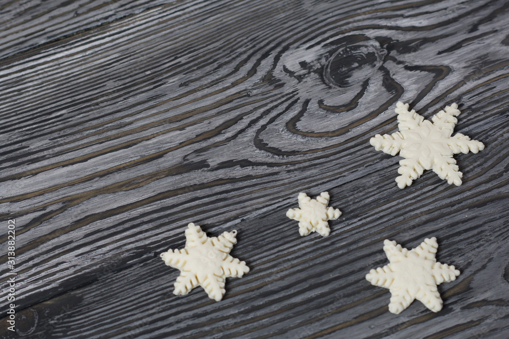 Heart shaped snowflakes made from pastilles. On old pine boards painted black.