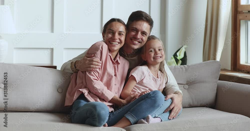 Happy man hugging wife and child daughter kissing on cheeks Happy man hugging wife and child daughter kissing on cheeks
