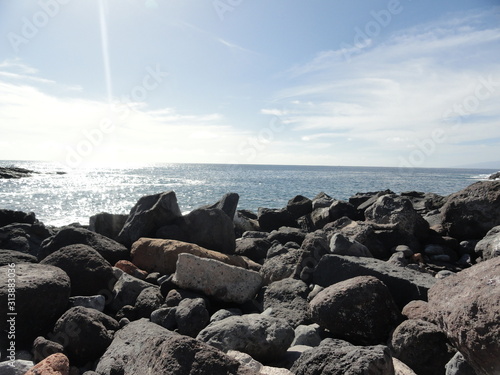 rocky coast, large boulders and sun glare on the sea