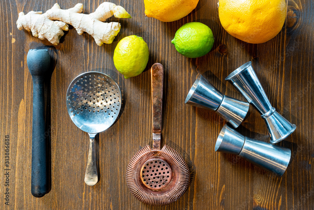 Set of a bartender accessories with fruits and ginger roots on a dark wooden table Set of a bartender accessories with fruits and ginger roots on a dark wooden table