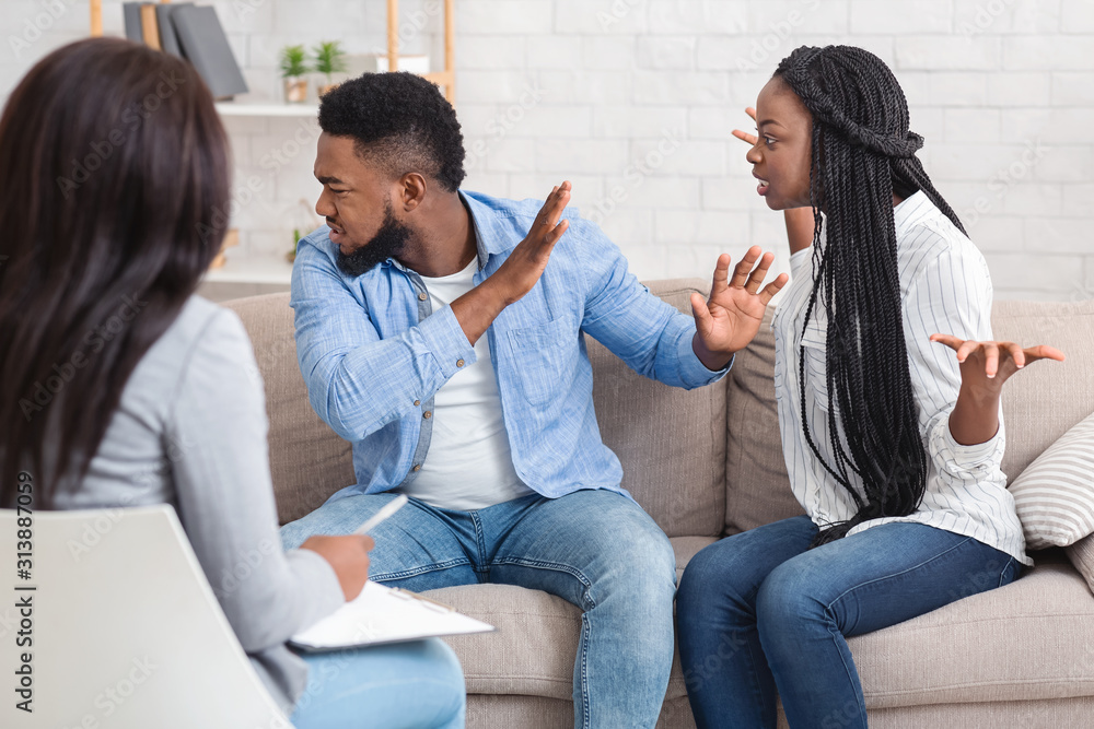 Emotional black couple quarreling at counselors office during therapy session Emotional black couple quarreling at counselors office during therapy session
