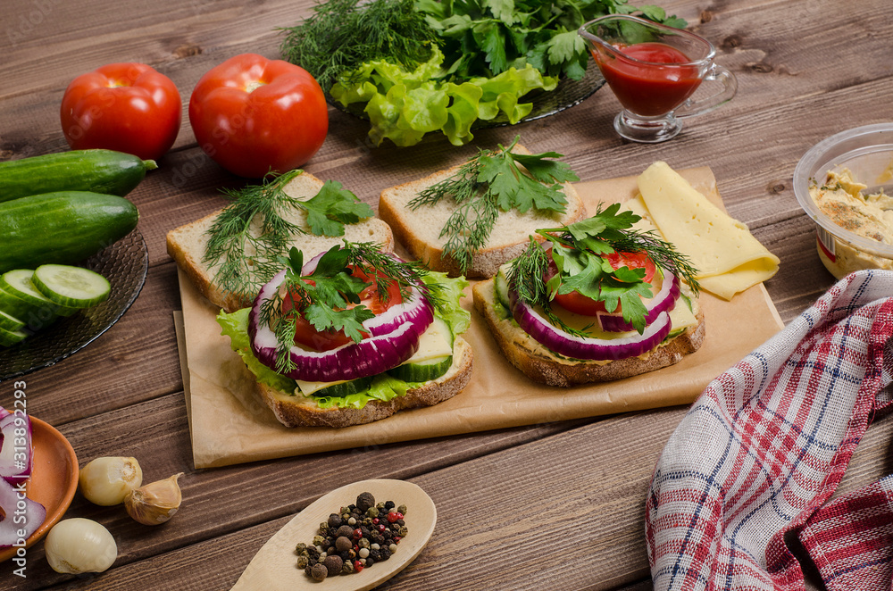Vegetarian sandwiches with hummus on a wooden board with ingredients on a dark wooden background. For advertising, menu.