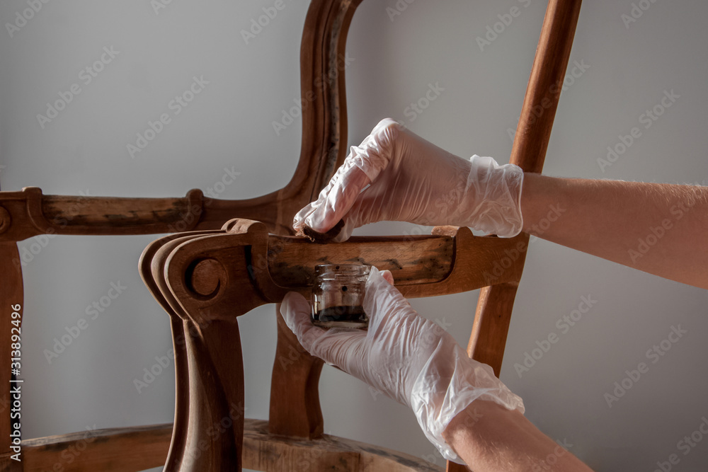 processing furniture stain with a swab made of lint-free cloth. all parts backrest, armrest, leg. Renovation of old furniture as an antique Victorian old wooden armchair. - obrazy, fototapety, plakaty 