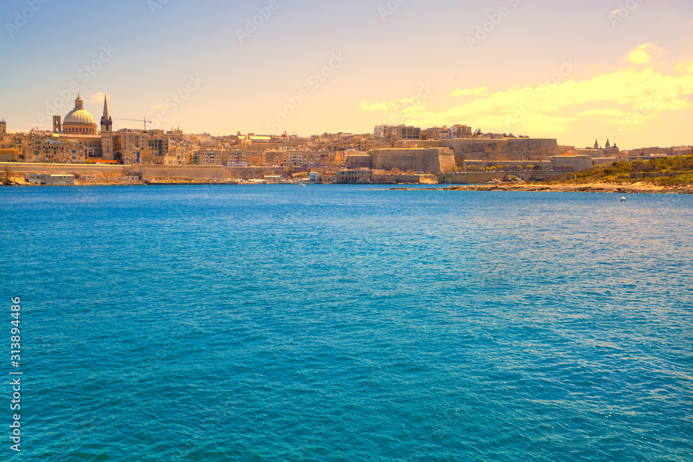 Malta, Sliema. Panoramic view of Mediterannean sea and old town buildings, colorful bright sky. 