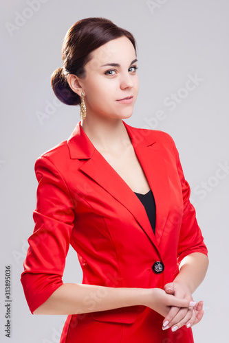 Portrait of Stylish and Fashionable Caucasian Woman in Red Blazer Posing Against Gray in Studio photo