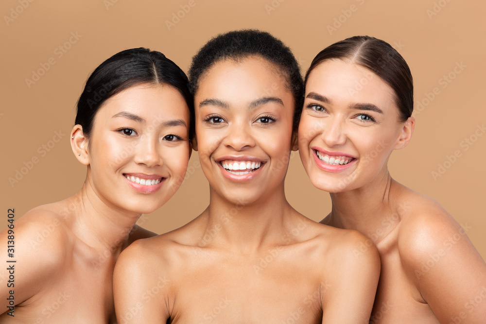 Three Multicultural Ladies Models Posing Smiling On Beige Studio Background Three Multicultural Ladies Models Posing Smiling On Beige Studio Background