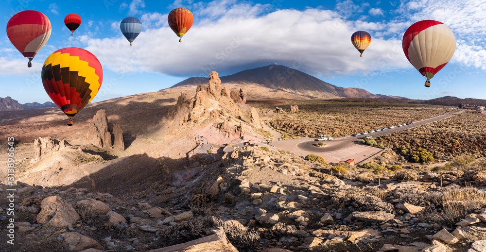 Obraz premium Landscape with hot air balloons flying in Teide National Park, Tenerife, Canary Islands, Spain. In background Roques de Garcia stone and Teide mountain volcano