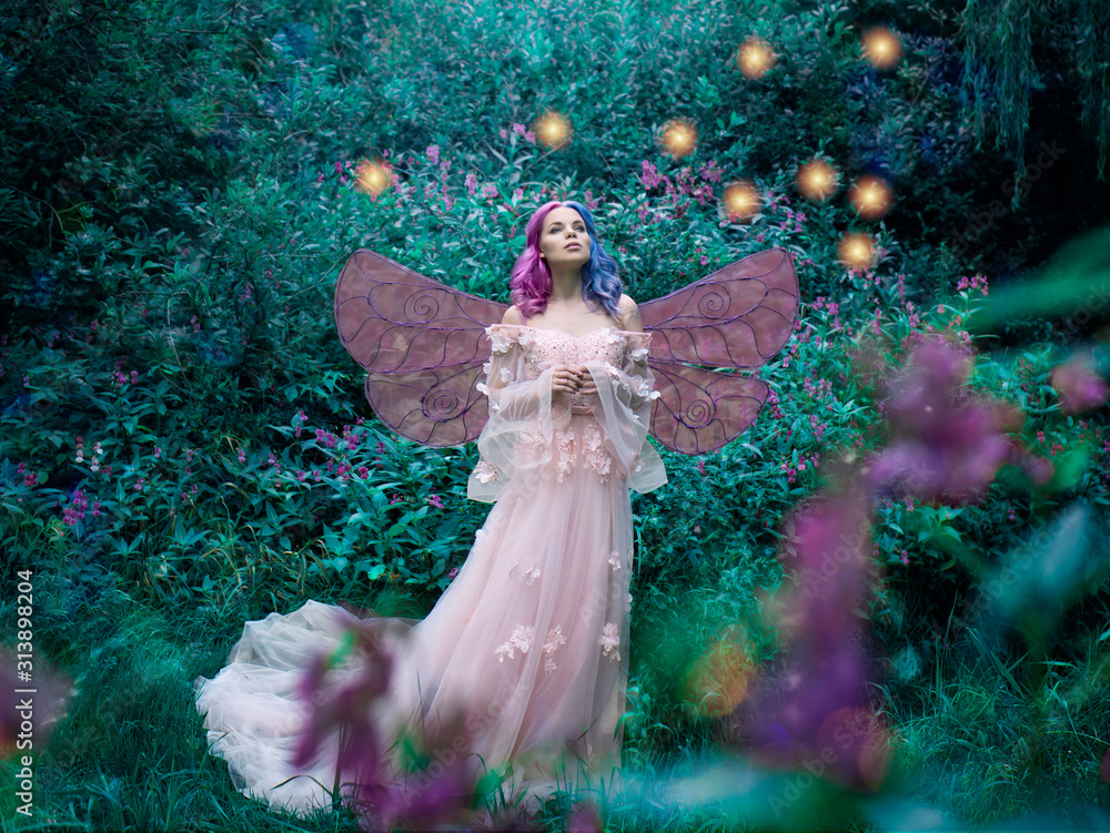 Fototapeta premium Fotografia artystyczna wróżki w różowej sukience w lesie ze świetlikami