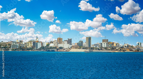 View of the Senegal capital of Dakar, Africa. It is a city panorama taken from a boat. There are large modern buildings and a blue sky with clouds. © Jana