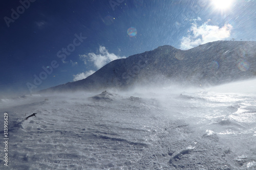 Whirlwind on snowy hilss in Slovakia Low Tatras. Epic wind storm in january with clear sky. Frozen land and snow attack on skier from side. Unpleasant side wind.