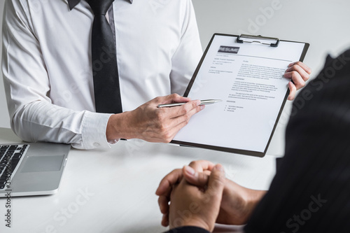 Employer or committee holding reading a resume with talking during about his profile of candidate, employer in suit is conducting a job interview, manager resource employment and recruitment concept