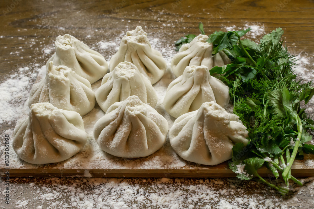 Fresh khinkali made from dough with meat inside, a national Georgian dish. Fresh dough, flour and herbs. Fresh khinkali made from dough with meat inside, a national Georgian dish. Fresh dough, flour and herbs.