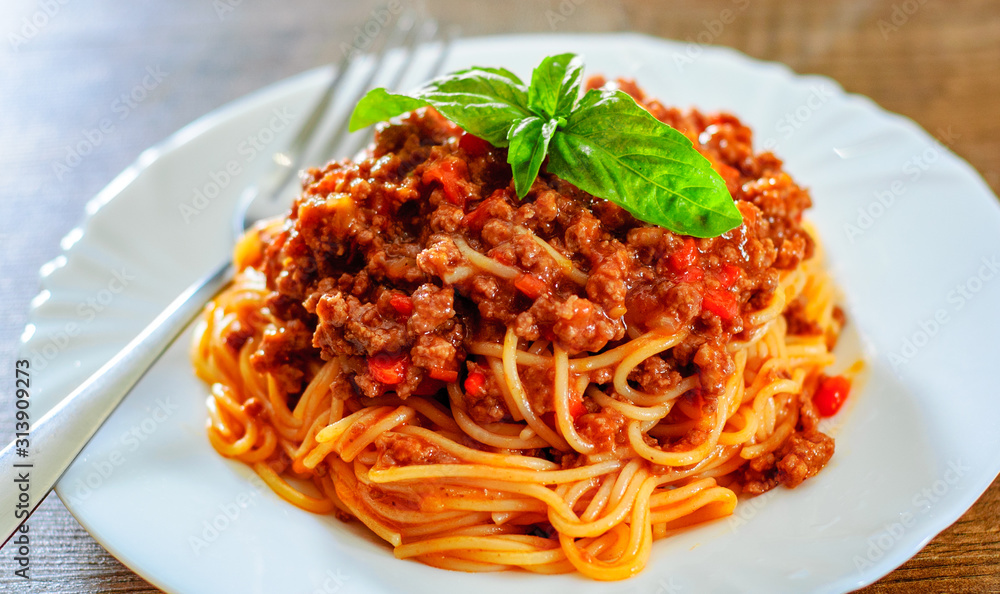 Traditional pasta spaghetti bolognese in white plate on wooden table background