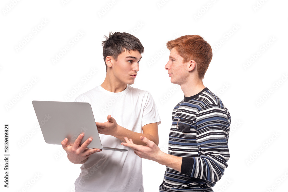 Two serious teenager guys are engaged on a laptop and discussing something, isolated Two serious teenager guys are engaged on a laptop and discussing something, isolated