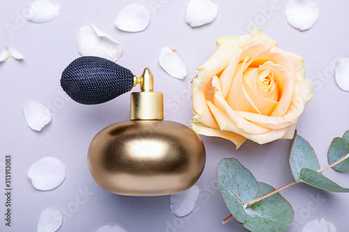 Bottle of perfume with rose flower and eucalyptus on grey background