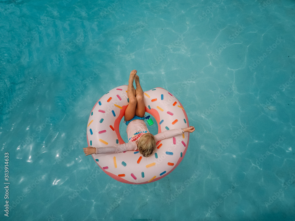 little girl sitting in pool with donut pool float Stock Photo | Adobe Stock