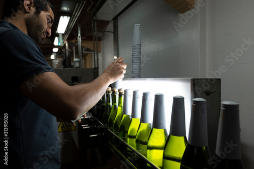 Attentive man placing foil caps on bottles photo