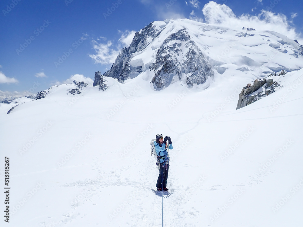 A young woman alpinist takes a photo while on a glacier A young woman alpinist takes a photo while on a glacier
