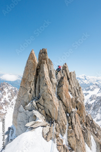 A seasoned alpinist rappels a spectacular gendarme on the Forbes Ridge photo