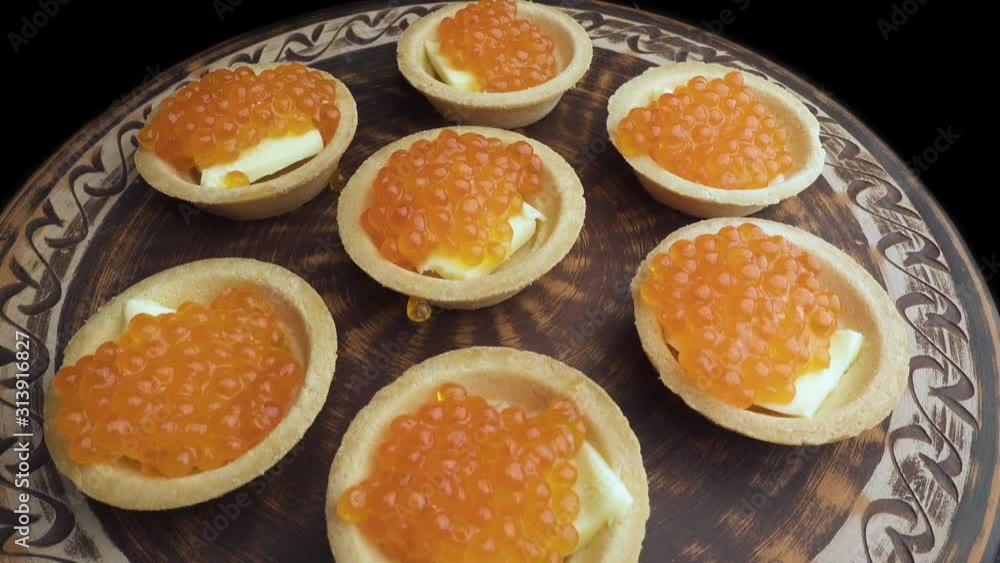 Red caviar is put with a spoon on tartlets. Preparation of snacks with red caviar. Top view. Rotation. Close up Red caviar is put with a spoon on tartlets. Preparation of snacks with red caviar. Top view. Rotation. Close up