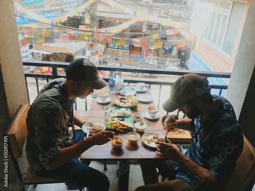 Two young men eating colorful meal on rooftop in Asia photo