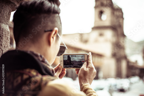 androgynous traveler takes photo on phone of church square photo