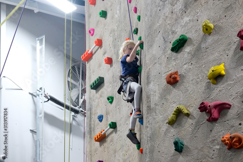 young girl climbing rock wall at indoor rock  climbing gym photo