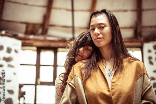 Same sex lesbian couple smile and cuddle in stone dome studio photo