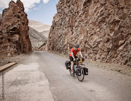 A cyclist rides through a rock cut on a mountain road in Morocco photo