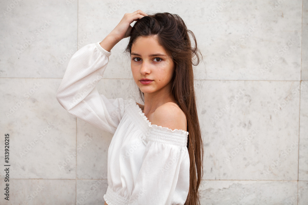 Young beautiful girl on a background of a white marble wall Young beautiful girl on a background of a white marble wall