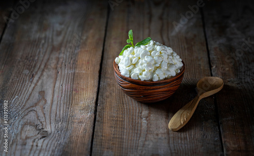 Granulated cottage cheese in a ceramic bowl on a wooden background. Healthy eating concept.