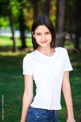 Исфдьeautiful brunette girl in white t-shirt on a background of a summer park
