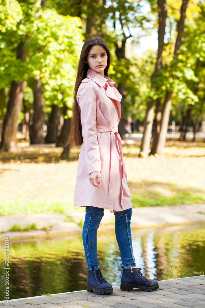Portrait of a young brunette girl in pink coat on a background of autumn park Portrait of a young brunette girl in pink coat on a background of autumn park