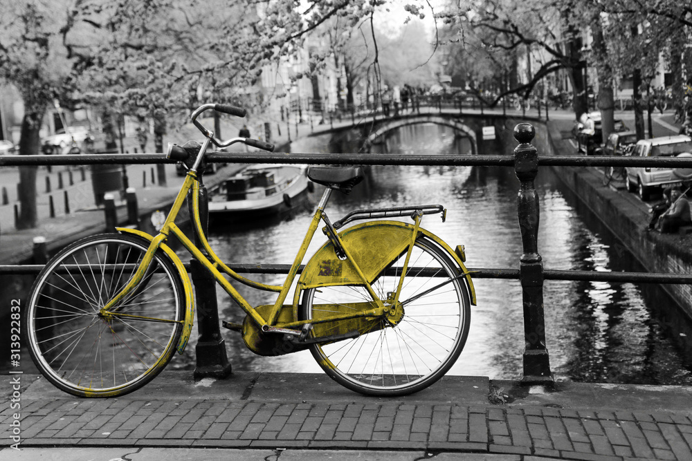 A picture of a lonely azure bike on the bridge over the channel in Amsterdam. The background is black and white.