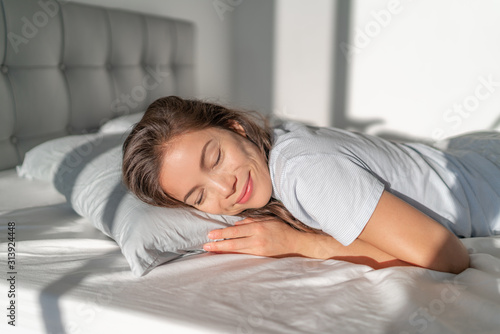 Bed Asian girl happy smiling sleeping on stomach sleeper resting head on foam pillow. Healthy sleep.