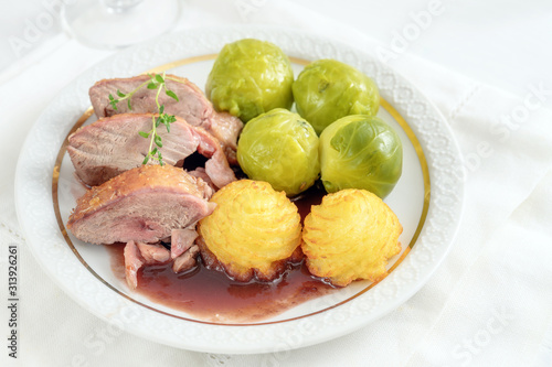 Tenderly roasted duck breast fillet with brussels sprout and duchess potatoes on a white plate, a festive dinner for holidays photo