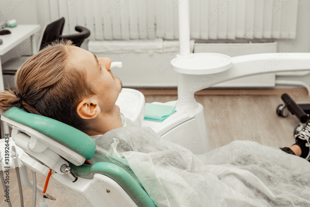A young and satisfied male patient in the dentist's chair. Smiling at the camera. Health and medicine. A young and satisfied male patient in the dentist's chair. Smiling at the camera. Health and medicine.