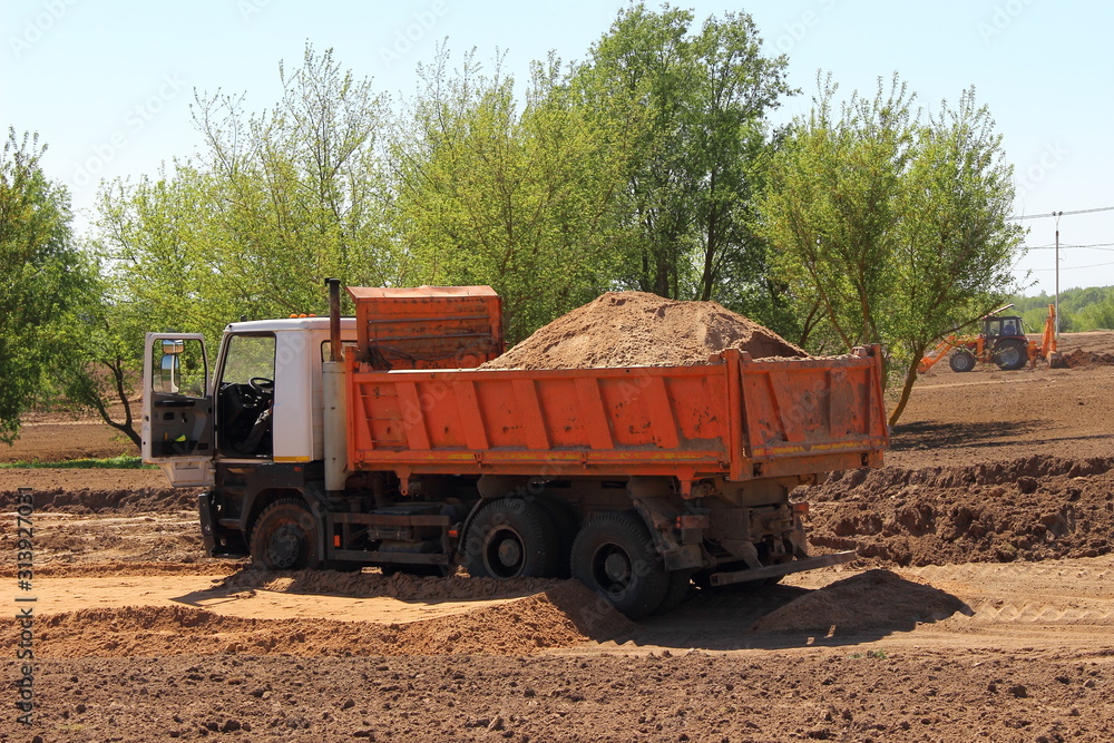 Heavy sand load dumper truck on ground construction site on Sunny summer day, bulk cargo transportation Heavy sand load dumper truck on ground construction site on Sunny summer day, bulk cargo transportation