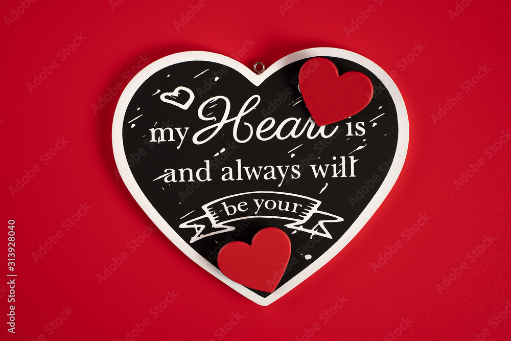 Black heart with an inscription-a Declaration of love, with red hearts, on a red background for Valentine's Day, wedding, birthday and other holidays, view from the top.