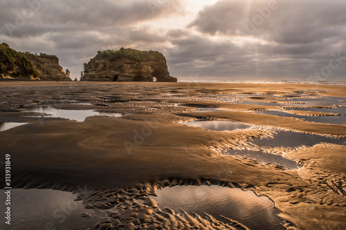 The reflection of sunset light in low tide sea water puddles with elephant rock in the background